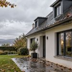 Maison avec toiture et gouttière sous la pluie après une tempête, illustration de l’assurance habitation et du défaut d’entretien