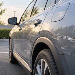 Voiture grise rayée sur le côté arrière, stationnée sur un parking extérieur